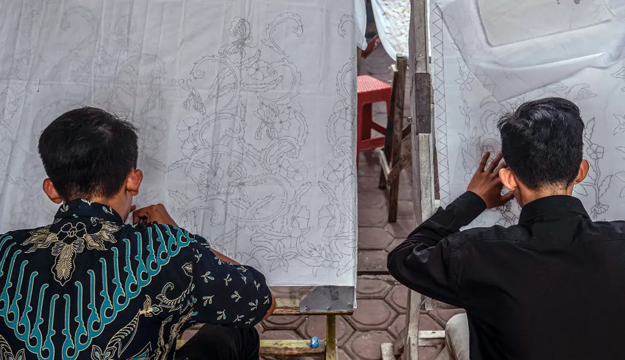 Pembuat batik menggambar pola pada kain saat proses pembuatan di Sidoarjo, Jawa Timur, Sabtu (1/10/2022). Indonesia akan memperingati Hari Batik Nasional pada 2 Oktober. (JUNI KRISWANTO/AFP)