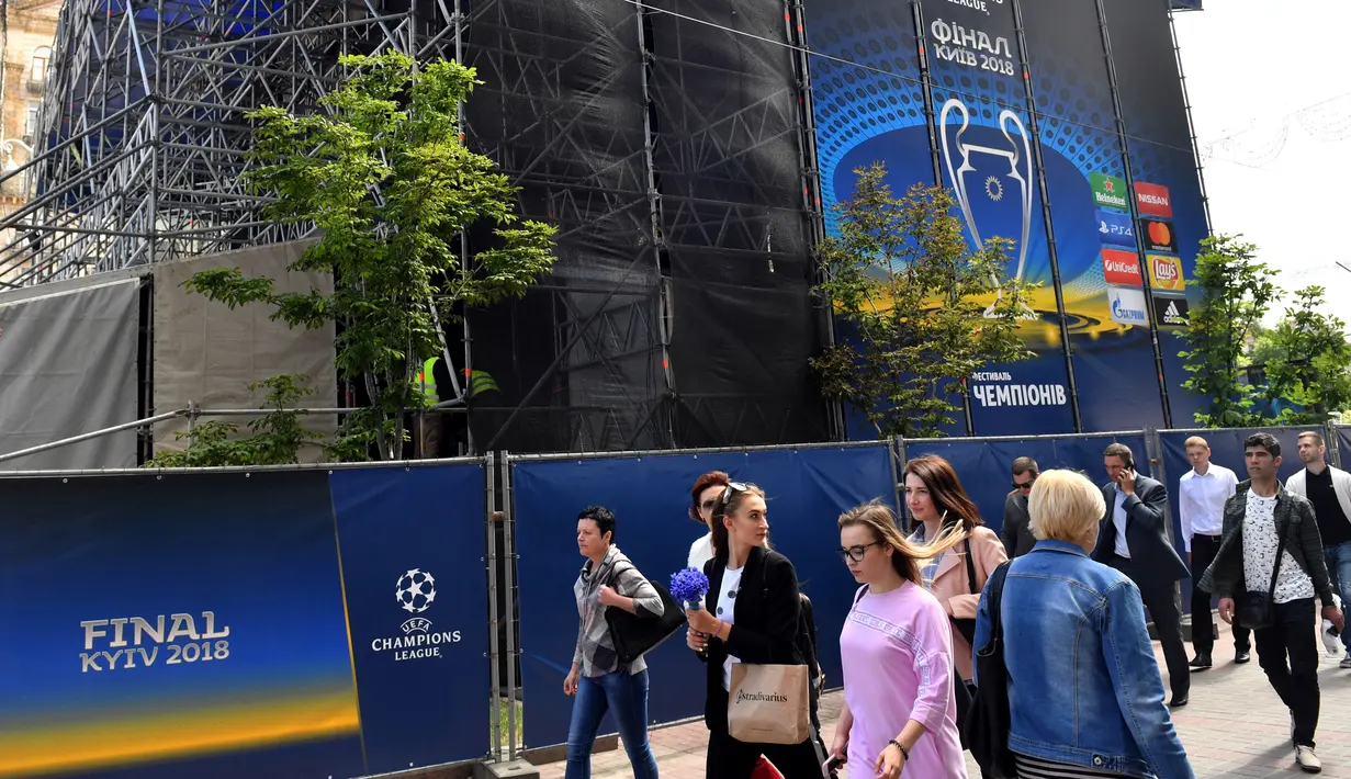 Orang-orang berjalan melewati zona pendukung menjelang final Liga Champions antara Real Madrid dan Liverpool FC di Kiev, Ukraina, Senin (21/5). Final Liga Champions akan berlangsung di Olimpiyskiy Stadium. (Sergei SUPINSKY/AFP)