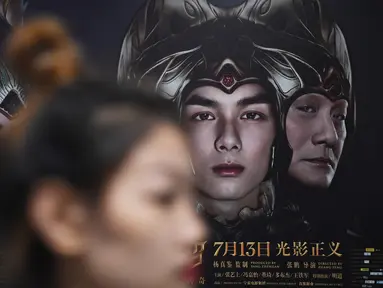 Seorang wanita berjalan melewati poster film Asura di stasiun kereta bawah tanah di Beijing, Selasa (17/7). Tim produser secara tiba-tiba menarik kembali Asura, film termahal di China yang baru tayang sepekan di bioskop. (AFP/GREG BAKER)
