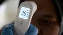 Seorang petugas kesehatan memeriksa suhu tubuh sebelum memberikan vaksin penguat virus corona Covid-19 Inavac di Bandara I Gusti Ngurah Rai, Bali, pada 29 Desember 2023. (SONNY TUMBELAKA/AFP)