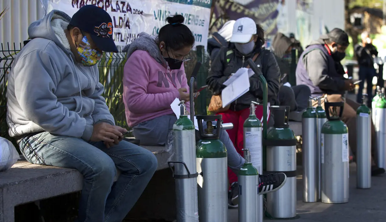 Orang-orang menunggu untuk mengisi ulang tangki oksigen bagi kerabat mereka yang menderita COVID-19 di Distrik Iztapalapa, Mexico City, Meksiko, Selasa (26/1/2021). Mexico City menawarkan isi ulang oksigen gratis untuk pasien COVID-19. (AP Photo/Marco Ugarte)