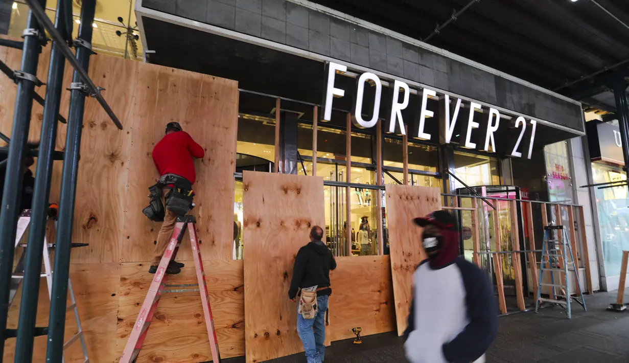 Para pekerja memasang papan pelindung pada sebuah toko di Times Square di New York, Amerika Serikat, pada 1 November 2020. Langkah tersebut dilakukan saat para peretail berupaya melindungi properti dari penjarahan atau kerusuhan lainnya dalam beberapa hari mendatang. (Xinhua/Wang Ying)