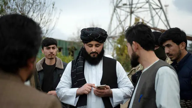Foto ini diambil pada 17 Januari 2022 menunjukkan Wali Kota Maymana Damullah Mohibullah Mowaffaq (tengah) melihat ponselnya di Maymana, ibu kota provinsi barat laut Faryab Afghanistan. (AFP)