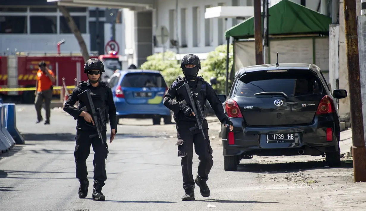 Aparat kepolisian bersenjata lengkap berjaga setelah serangan bom bunuh diri di Polrestabes Surabaya, Jawa Timur, Senin (14/5). Polisi mendata ada 10 korban luka dalam tragedi bom bunuh diri di Markas Polrestabes Surabaya. (AFP/JUNI KRISWANTO)