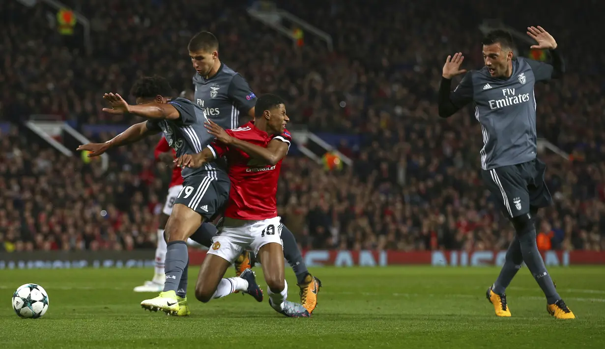Striker Manchester United, Marcus Rashford, terjatuh saat berebut bola dengan bek Benfica, Eliseu, pada laga Liga Champions di Stadion Old Trafford, Selasa (31/10/2017). Manchester United menang  2-0 atas Benfica. (AP/Dave Thompson)