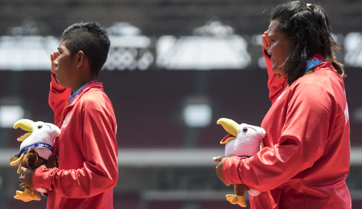 Atlet tolak peluru Indonesia, Suparniyati, hormat bendera saat seremoni usai meraih medali emas Asian Para Games 2018 di SUGBK, Jakarta, Senin (8/10/2018). (Bola.com/Vitalis Yogi Trisna)