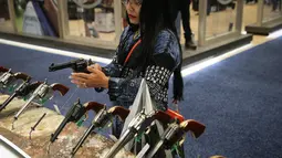 Seorang wanita menjajal pistol di Kay Bailey Hutchison Convention Center saat konvensi tahunan NRA, Texas (6/5). Acara pameran senjata ini dihadiri sekitar 70.000 peserta. (AFP/Loren Elliot)