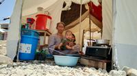 Seorang ibu dan anaknya sedang berteduh di dapur huniannya saat suhu panas terjadi di Kota Palu, Rabu ( 22/1/2020 ). (Liputan6.com/Heri Susanto)