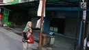 Warga berjalan di antara pertokoan yang tutup usai kerusuhan di Mako Brimob Kelapa Dua, Depok, Jawa Barat, Rabu (9/5). Korban meninggal dilaporkan terdiri dari lima anggota polisi dan seorang napi teroris. (Liputan6.com/Immanuel Antonius)