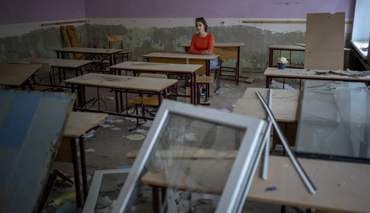 Dikelilingi oleh pecahan kaca dan puing-puing Sofia Zhyr (14) duduk di mejanya di sisa-sisa ruang kelasnya di Chernihiv School #21, yang dibom oleh pasukan Rusia pada 3 Maret, di Chernihiv, Ukraina, Selasa, 30 Agustus 2022. Banyak sekolah Ukraina dibuka kembali pada 1 September untuk pertama kalinya sejak invasi Rusia dimulai pada 24 Februari lalu. (AP Photo/Emilio Morenatti)