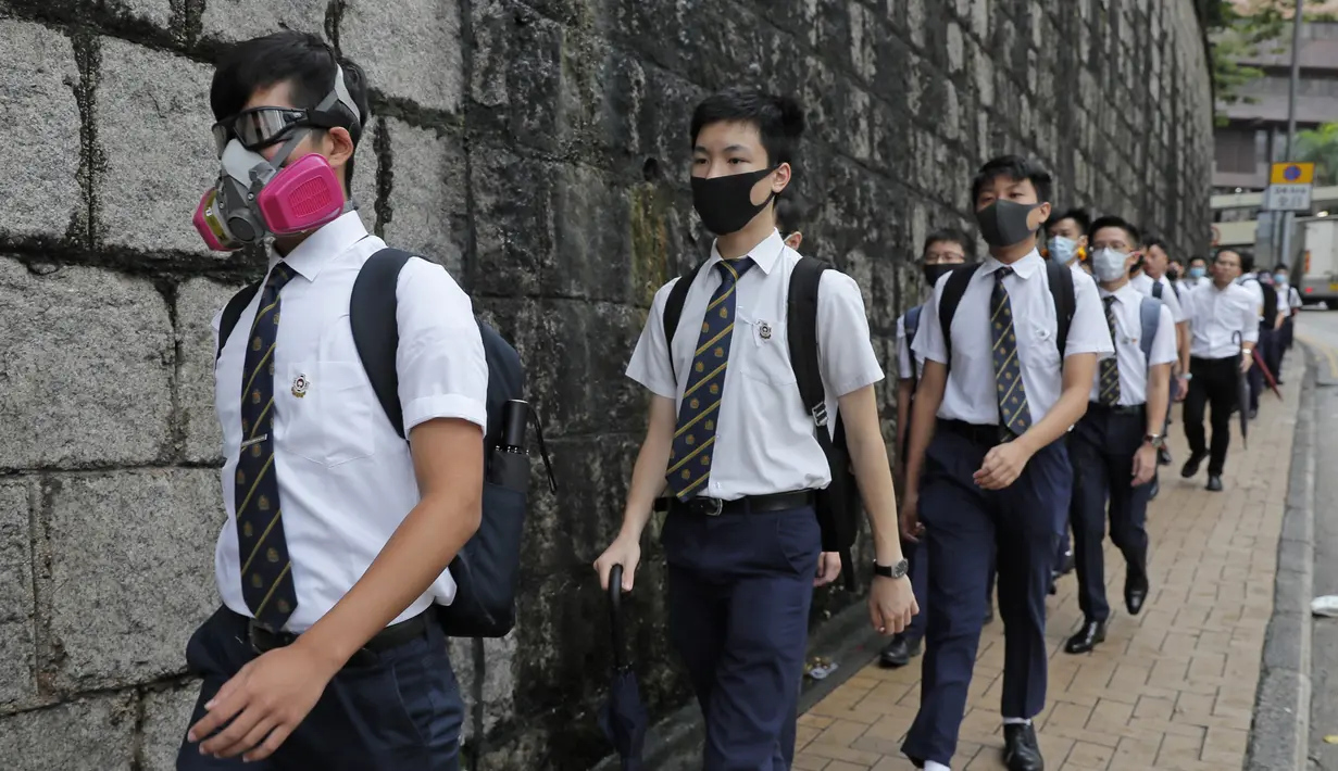 Para siswa sekolah mengenakan topeng dan helm berjalan di luar St. Paul's College selama protes di Hong Kong, Selasa (3/9/2019). Puluhan ribu siswa di Hong Kong memprotes terhadap gerakan anti-pemerintah. (AP Photo/Kin Cheung)