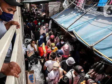 Seorang pria mengamati dari atas kerumuman pengunjung yang memadati Pasar Tanah Abang, Jakarta Pusat, Minggu (2/5/2021). Pusat Grosir Pasar Tanah Abang ramai didatangi pengunjung yang berbelanja menjelang Lebaran dengan berdesak-desakan tanpa jaga jarak. (Liputan6.com/Johan Tallo)