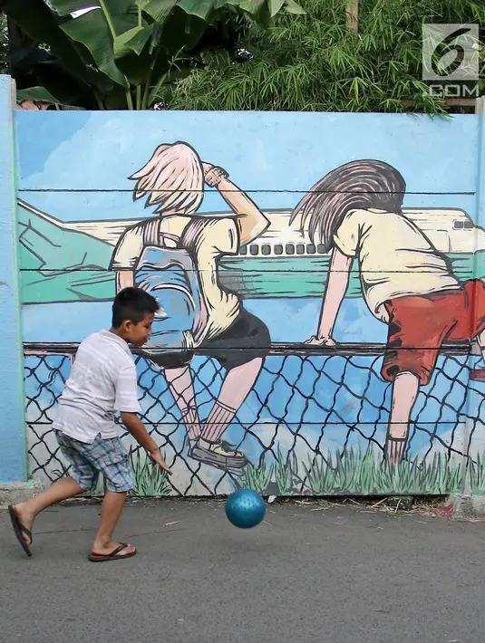 Seorang anak kecil bermain bola di sisi tembok yang terdapat lukisan mural di kawasan Kramat Jati, Jakarta, Rabu (4/4). Mural-mural antara lain membawa pesan menjaga kebersihan, bahaya narkoba hingga pencegahan kekerasan. (Liputan6.com/Herman Zakharia)