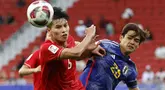 Pemain Vietnam, Nguyen Thanh Binh (kiri) berebut bola dengan pemain Jepang, Kaishu Sano pada laga Grup D Piala Asia 2023 di Al Thumama Stadium, Qatar, Minggu (14/01/2024). (AFP/Karim Jaafar)