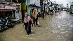 Warga berjalan melewati banjir rob di kawasan Muara Angke, Jakarta, Selasa (9/11/2021). Badan Penanggulangan Bencana Daerah (BPBD) DKI Jakarta memperkirakan puncak musim hujan dan potensi rob di Ibu Kota terjadi pada Januari hingga Februari 2022. (Liputan6.com/Faizal Fanani)