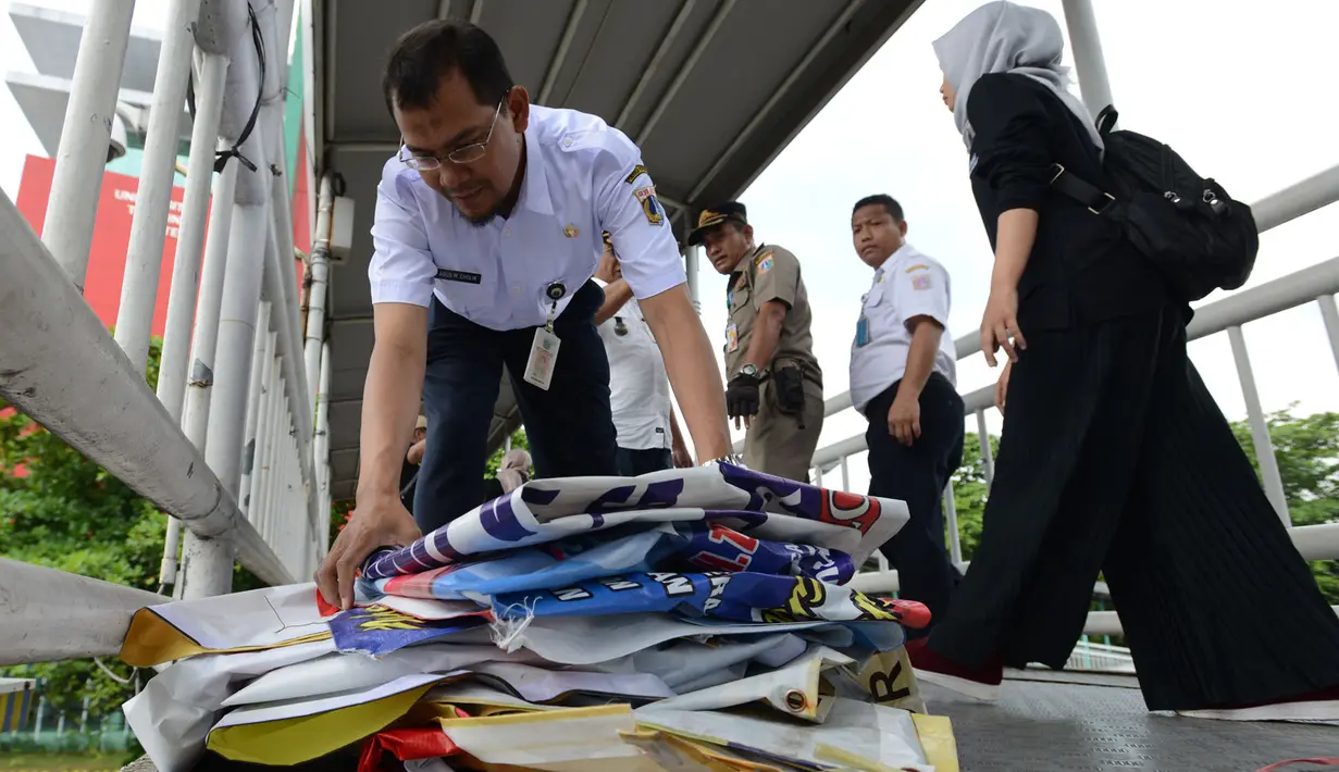 Petugas menertibkan Alat Peraga Kampanye (APK) Pilpres, Caleg dan Partai Politik di Kawasan Jalan Pemuda, Jakarta, Rabu (13/3). APK Pemilu 2019 yang terpasang pada JPO dibersihkan. (merdeka.com/Imam Buhori)