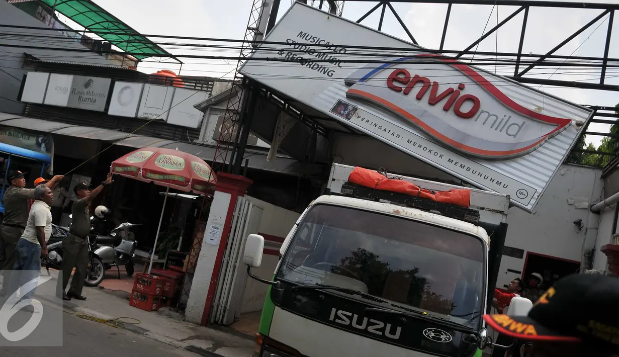 Petugas Satpol PP menurunkan papan reklame rokok di Jakarta, Rabu (18/11). Gubernur DKI Jakarta menerbitkan Peraturan Gubernur Nomor 1 Tahun 2015 tentang Larangan Penyelenggaraan Reklame Rokok Media Luar Ruang. (Liputan6.com/Gempur M Surya)