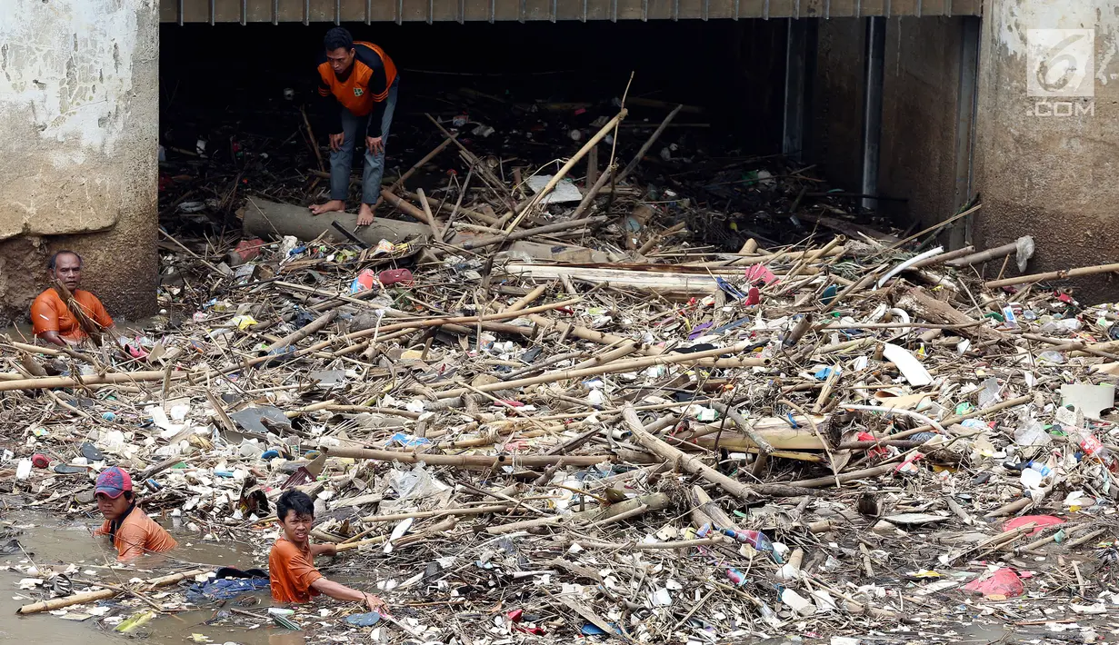 Pasukan Orange mencoba mengurai sampah di Pintu air Manggarai, Jakarta, Senin (2/10). Dinas Kebersihan DKI mengangkat sampah seberat 90-220 ton/hari dari badan air di sungai, waduk, setu dan danau di wilayah Ibu Kota. (Liputan6.com/Johan Tallo)