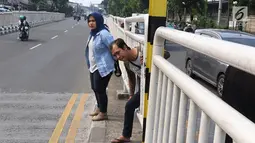 Warga menyeberang memanfaatkan pagar pembatas jalan di kawasan Pasar Minggu, Jakarta, Kamis (5/4). Kondisi Jembatan Penyeberangan Orang (JPO) yang tak kunjung diperbaiki membuat warga menyeberang lewat celah pagar pembatas (Liputan6.com/Immanuel Antonius)