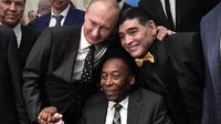 Legenda sepak bola, Diego Maradona dan Pele, foto bersama dengan Presiden Rusia, Vladimir Putin, saat menghadiri Drawing Piala Dunia 2018 di Kremlin Palace, Jumat (1/12/2017). Acara tersebut dihadiri legenda sepak bola dunia. (AFP/Alexey Nikolsky)