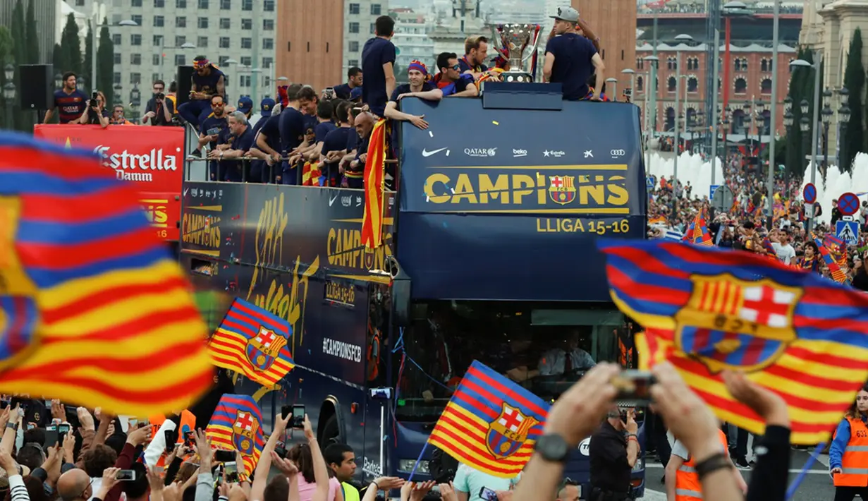 Suporter Barcelona menyambut tim Barcelona yang berpawai dengan menggunakan bus berkeliling kota untuk merayakan gelar La Liga ke-24, Minggu (15/5/2016). (AFP/Pau Barrena)