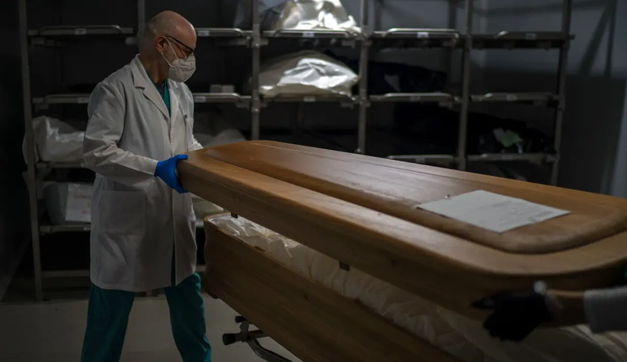Petugas kamar jenazah menutup peti jenazah korban COVID-19 di kamar jenazah Memora, Barcelona, Spanyol, 5 November 2020. Seperti dokter dan perawat, petugas kamar jenazah adalah bagian dari sekelompok pekerja penting di tengah pandemi. (AP Photo/Emilio Morenatti)