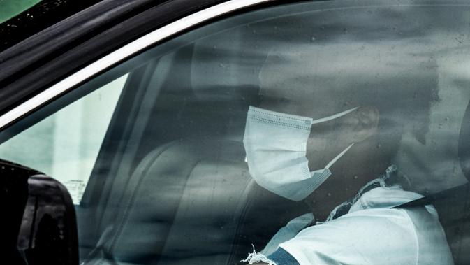 Pemain Juventus Juan Cuadrado terlihat mengenakan masker dalam mobilnya saat tiba untuk menghadiri latihan di Continassa, Turin, Italia, Selasa (19/5/2020). Pemain Juventus kembali berlatih di tengah pandemi virus corona COVID-19. (Miguel MEDINA/AFP)