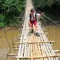 Seorang siswa SD melintas di atas jembatan gantung di atas kali Ciliwung untuk menuju ke sekolah, Jakarta, Selasa (17/3/2015). Jembatan tersebut menghubungkan Kelapa Dua Depok dengan Lenteng Agung (Liputan6.com/Yoppy Renato)