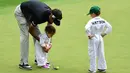 Pegolf Bubba Watson dari AS membantu putrinya Dakota putt saat mengikuti Masters Par 3 Tournament di Augusta National Golf Club, Georgia, (5/4). Anak-Anak ini menunjukkan keterampilannya bermain golf bersama orang tuanya. (Harry How/Getty Images/AFP)