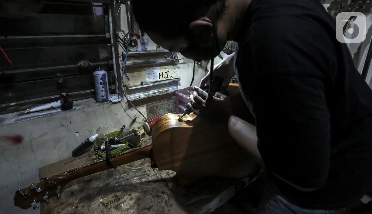 Harry saat mereparasi gitar klasik menjadi gitar listrik di toko kawasan Kedoya, Jakarta Barat, Selasa (9/2/2021). Turunnya servis gitar selama pandemi COVID-19 dikarenakan banyak pemilik gitar enggan untuk keluar rumah dan memilih untuk membeli gitar baru. (Liputan6.com/Johan Tallo)