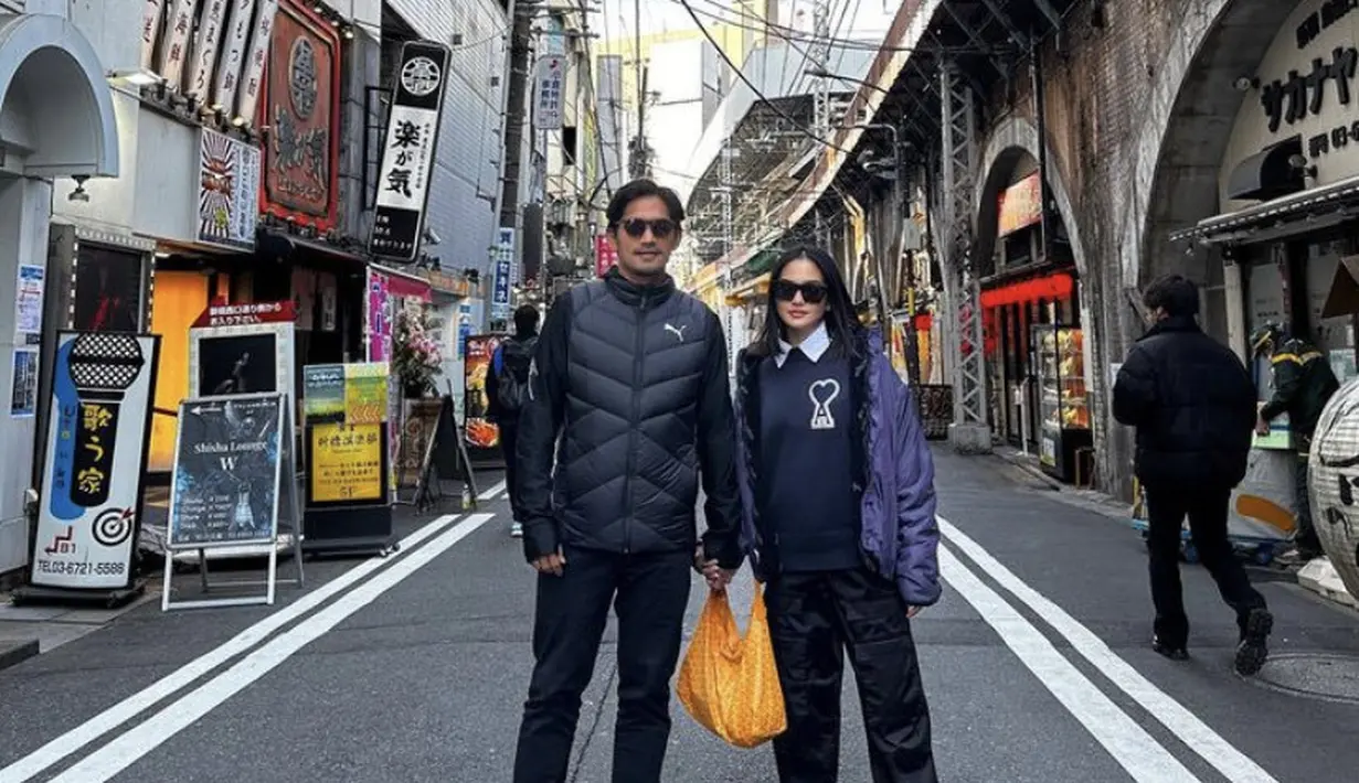 Bersama sang suami, Ririn tampil dengan jaket ungu dipadukan sweater hitam berkerah serasi dengan celananya. (@ririnekawati)