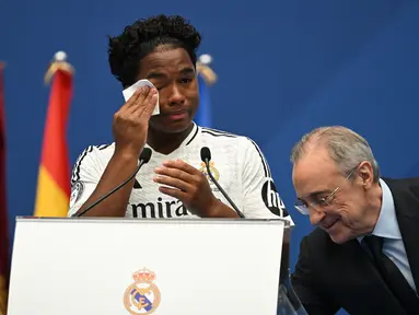 Pemain depan Brasil Endrick Felipe menyeka air matanya saat dia berdiri di samping presiden Real Madrid Florentino Perez selama penampilan pertamanya sebagai pemain baru Real Madrid di Stadion Santiago Bernabeu, Sabtu (27/7/2024). (JAVIER SORIANO / AFP)