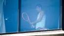 Petenis Australia, Bernard Tomic melakukan latihan dikamar hotel saat menjalani karantina selama dua minggu setelah kedatangannya di Melbourne, Minggu (17/1/2021). (Foto: AFP/William West)