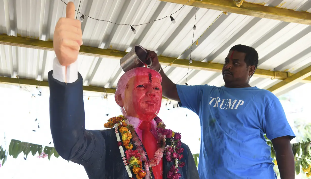 Bussa Krishna (33) saat memandikan patung Presiden AS Donald Trump di Desa Konney, Telangana, negara bagian India selatan (14/2/2020). Bussa Krishna merupakan penggemar berat Presiden AS, Donald Trump. (AFP/Noah Seelam)