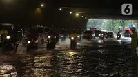 Pengendara sepeda motor menerjang banjir yang merendam terowongan di Cawang, Jakarta, Jumat (19/2/2021). Hujan yang turun sejak semalam membuat sejumlah jalanan di Ibu Kota tergenang banjir dengan ketinggian sekitar 30-50 cm. (merdeka.com/Imam Buhori)