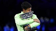 Carlos Alcaraz memeluk erat piala Australian Open 2026 yang didapatnya setelah menaklukkan Novak Djokovic dalam laga sengit yang dilangsungkan di Melbourne Park pada (1/2/2026) sore WIB. (AFP/Martin Keep)