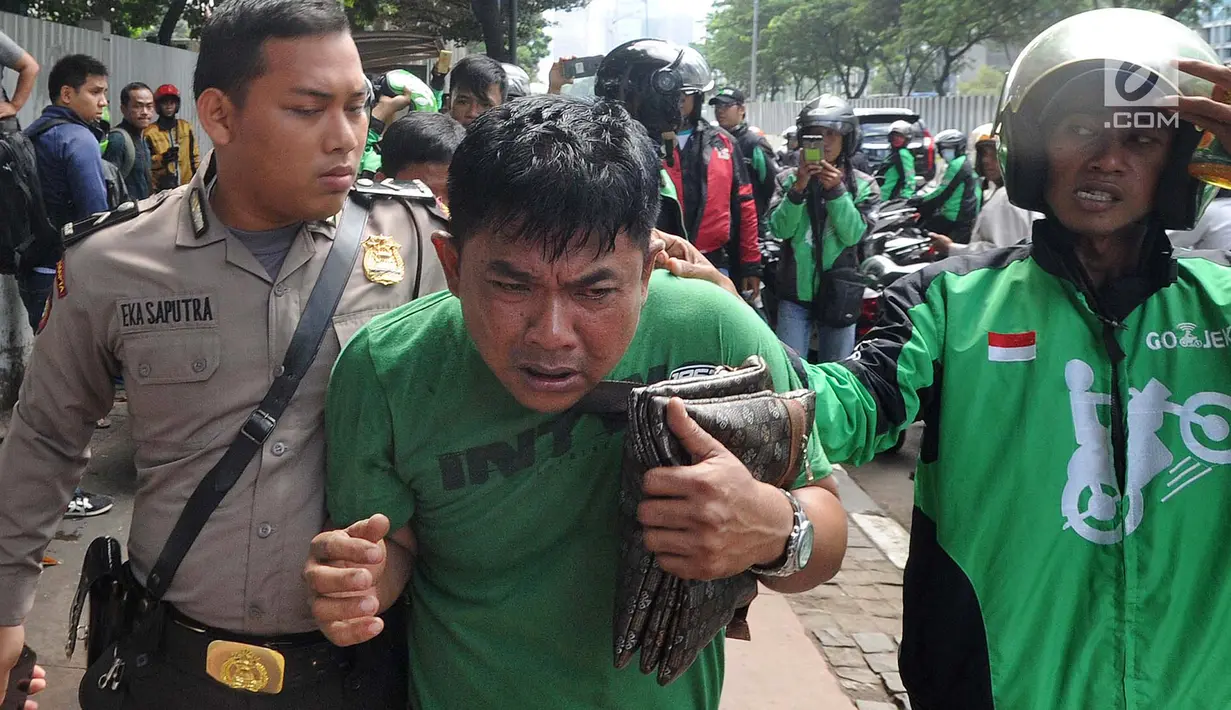 Petugas kepolisian mengamankan terduga copet menuju Mapolda Metro Jaya di Jalan Jenderal Sudirman, Jakarta (2/4). Pelaku tertangkap tangan oleh korbannya saat mencopet handphone di jembatan penyeberangan orang (JPO). (Merdeka.com/Arie Basuki)