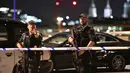 Dua polisi bersenjata memblokade kawasan London Bridge, setelah serangan teror, Sabtu (3/6). Serangan teror terjadi di London Bridge dan Borough Market, yang dilakukan lima orang pria dan menewaskan 6 orang termasuk pelaku. (Dominic Lipinski/PA via AP)