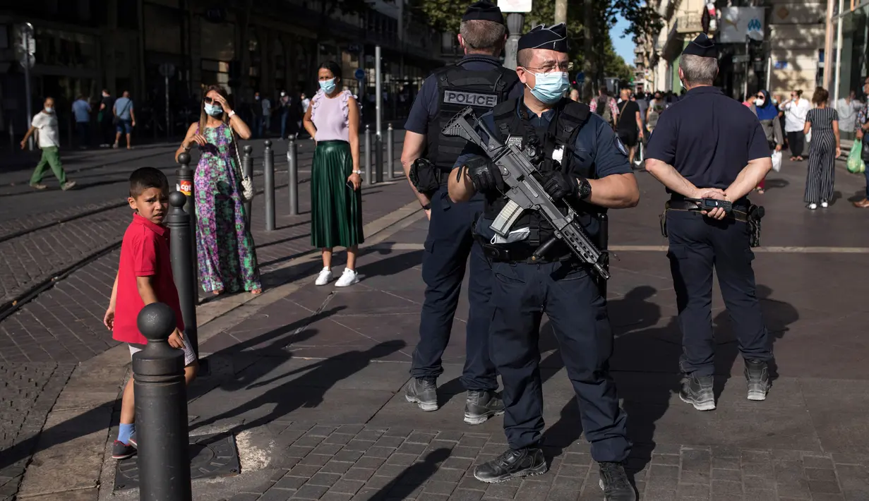 Polisi anti huru-hara Prancis mengamati warga yang mengenakan masker di Marseille, Selasa (18/8/2020). Pemerintah Prancis mengirim polisi anti huru hara ke wilayah Marseille untuk membantu menegakkan peraturan penggunaan masker saat negara itu mencatat lonjakan kasus COVID-19. (AP Photo/Daniel Cole)