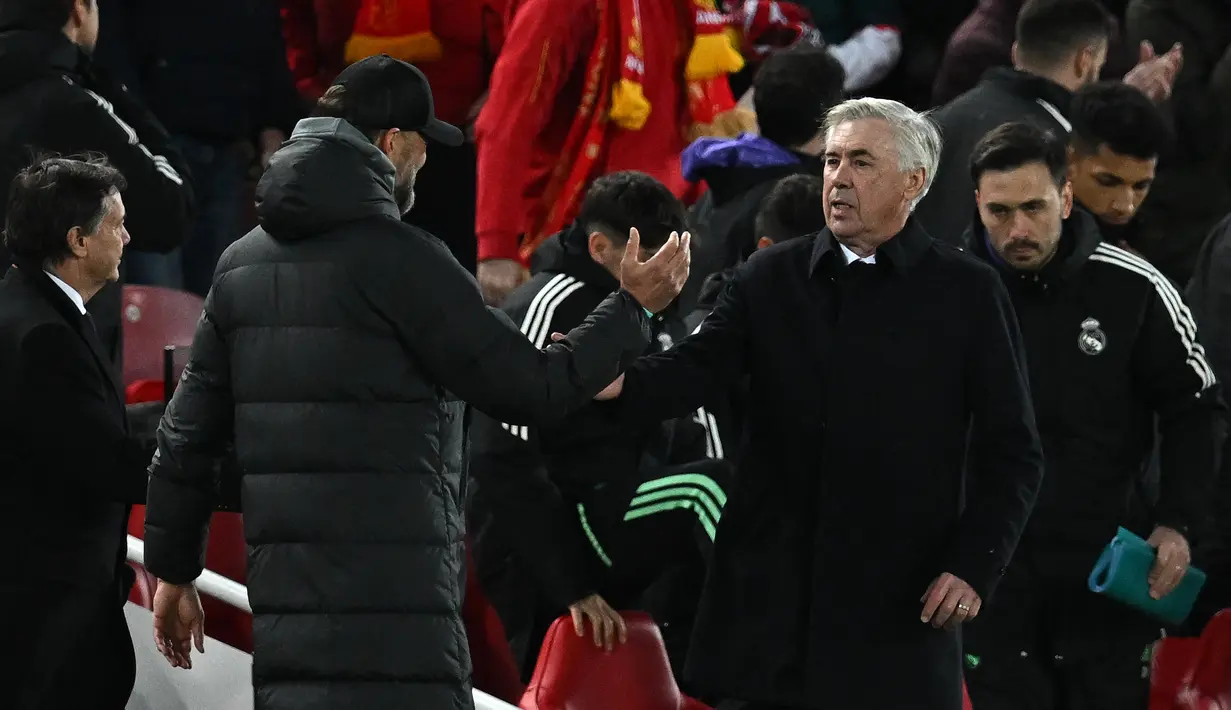 Pelatih Liverpool Jurgen Klopp (kiri) dan pelatih Real Madrid Carlo Ancelotti berjabat tangan usai pertandingan melawan Real Madrid pada pertandingan leg pertamababak 16 besar Liga Champions di stadion Anfield di Liverpool, Inggris, Rabu (22/2/2023). Liverpool kalah telak dari Madrid dengan skor 2-5. (AFP/Paul Ellis)