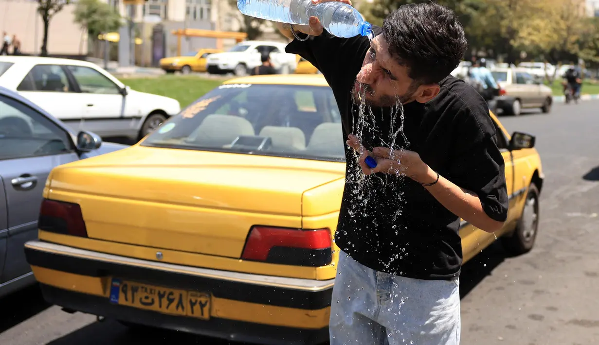 Seorang sopir taksi Iran mendinginkan diri dengan menyiramkan air ke wajahnya di sebuah jalan di tengah suhu yang melonjak di Teheran pada 22 Juli 2025. (Foto oleh AFP)