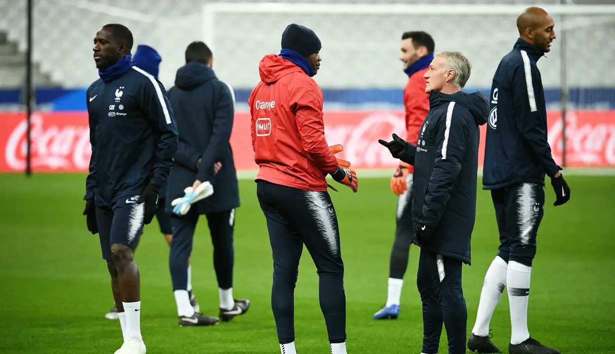Pelatih Prancis, Didier Deschamps, berbincang dengan Steve Mandanda saat sesi latihan di Stade De France, Paris, Minggu (19/11/2018). Prancis akan mejalani laga persahabatan melawan Uruguay. (AFP/Franck Fife)