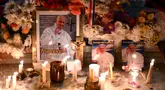 Lilin dan bunga diletakkan di samping foto mendiang Paus Fransiskus di pintu masuk Katedral Buenos Aires, Argentina pada tanggal 21 April 2025. (Luis ROBAYO/AFP)