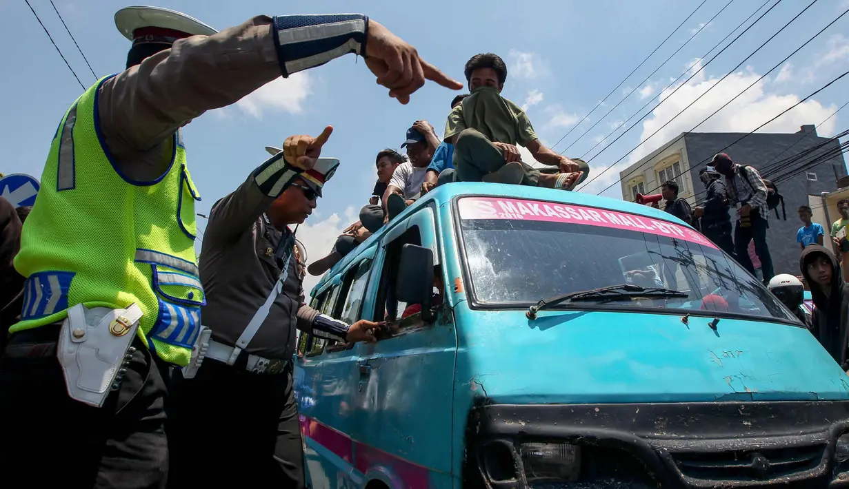 Polisi berjaga saat sopir angkutan konvensional demo transportasi online di Jalan Urip Sumoharjo, Makassar, Rabu (1/11). Para pendemo gagal menemui Gubernur Sulsel yang menyebabkan para pendemo mengamuk. (AFP Photo/Yusuf Wahil)