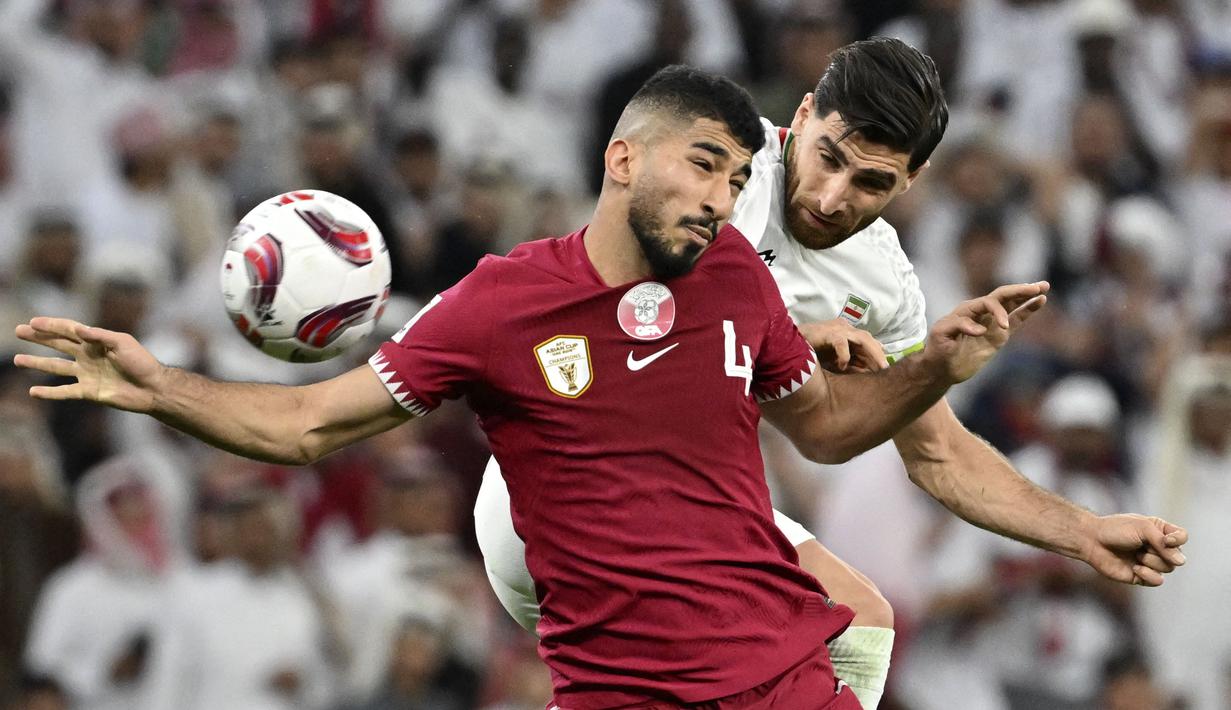 Pemain Qatar, Mohammed Waad (kiri) berduel udara dengan pemain Iran, Alireza Jahanbakhsh pada laga semifinal Piala Asia 2023 di Al Thumama Stadium, Doha, Qatar, Rabu (07/02/2024). (AFP/Hector Retamal)