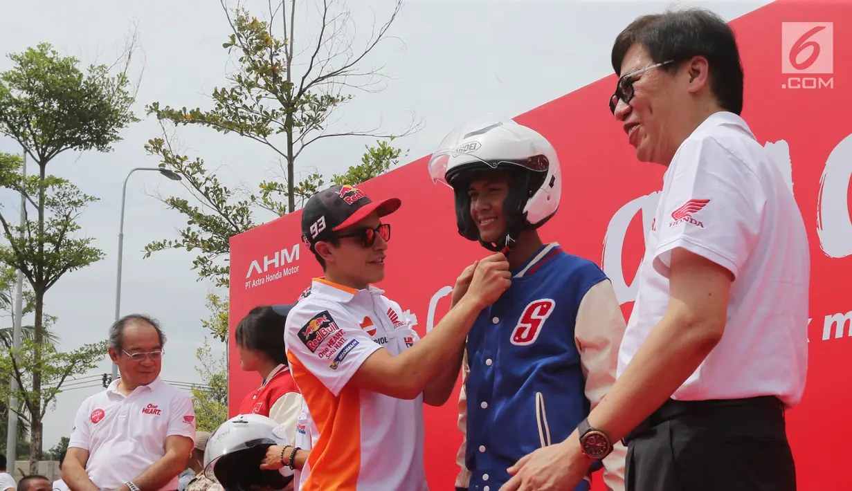 Pembalap MotoGP Marc Marquez secara simbolik memakaikan helm dan jaket kepada perwakilan siswa SMK saat acara kampanye keselamatan berkendara di BSD, Tangerang Selatan (10/17). (Liputan6.com/Pool/Bon)