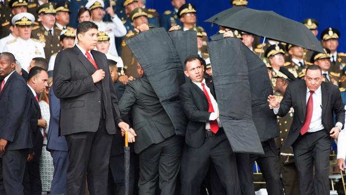 Pengawal melindungi Presiden Venezuela Nicolas Maduro dengan perisai antipeluru saat serangan drone di Caracas, Venezuela, Sabtu (4/8). Serangan terjadi saat Presiden Maduro berpidato dalam HUT ke-81 Tentara Venezuela. (Xinhua via AP)