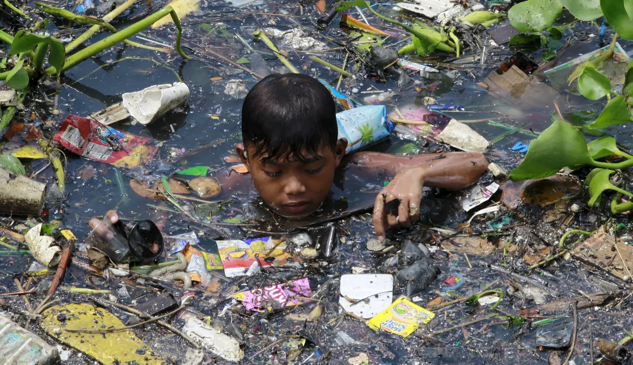 Seorang Anak laki-laki memilah sampah yang terapung untuk di jadikan bahan daur ulang di sebuah sungai yang tercemar di kota navotas, Manila, Kamis (2/7/2015). Daur ulang bertujuan untuk mengurangi tingkat pencemaran sungai. (REUTERS/Romeo Ranoco)