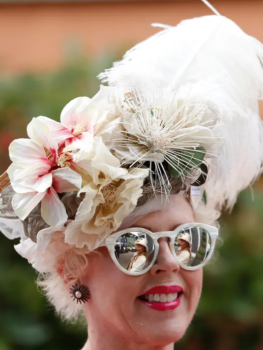 Seorang wanita mengenakan topi atau fascinator unik bermotif bunga saat menghadiri ajang pacuan kuda Royal Ascot di Ascot, Inggris, Selasa (18/6/2019). Royal Ascot menjadi ajang bagi wanita Inggris untuk tampil dengan fascinator unik. (AP Photo/Alastair Grant)