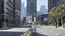 Seorang pekerja dengan pakaian pelindung berdiri di tengah jalan-jalan kosong di area penguncian di distrik Jingan, Shanghai barat (4/4/2022). Pengiriman petugas kesehetan untuk membasmi wabah COVID-19 yang menyebar dengan cepat di kota terbesar di China. (AP Photo/Chen Si)